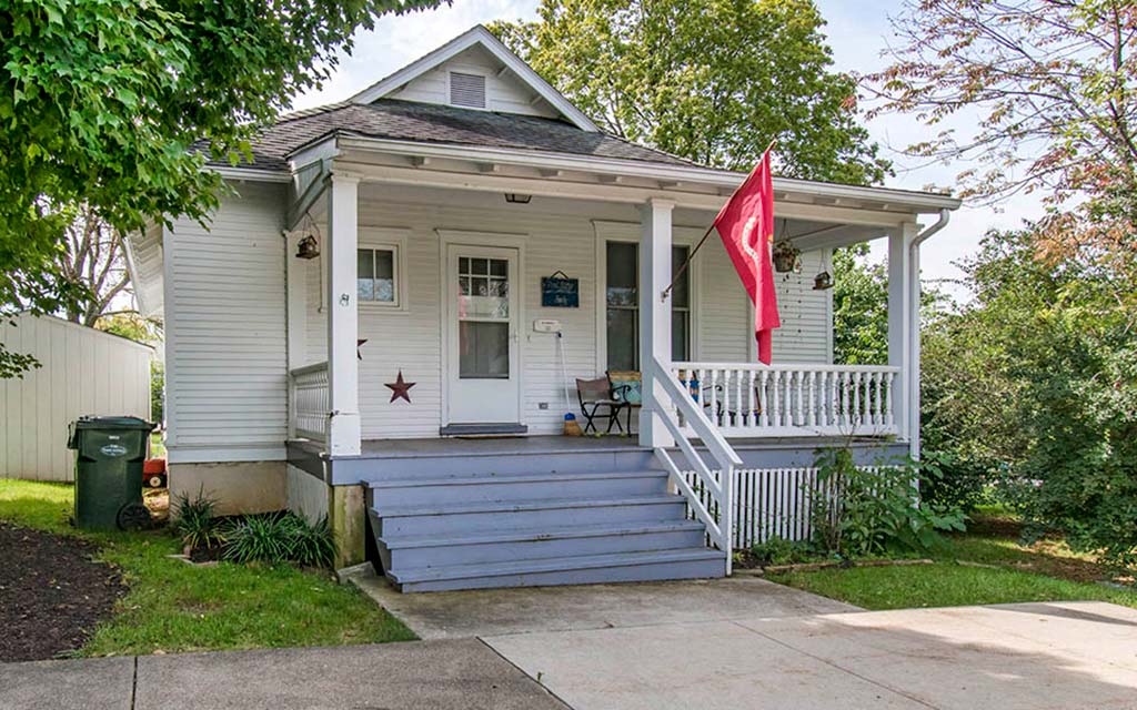 a small white house with a flag on the porch