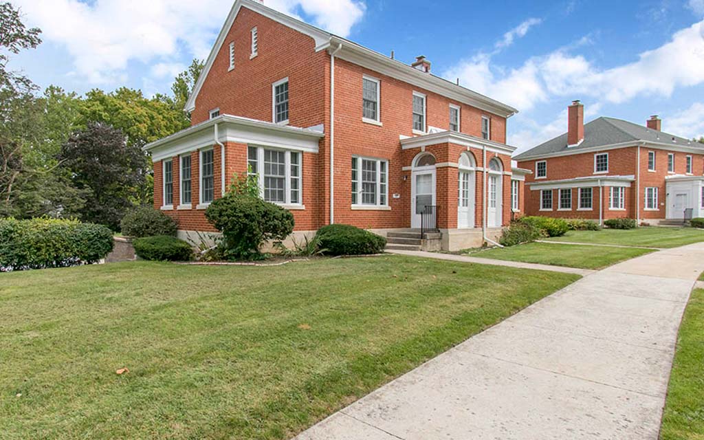 a red brick house with a sidewalk in front of it