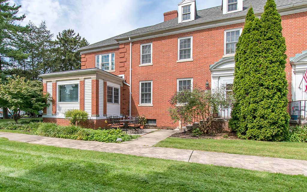 a brick house with a sidewalk in front of it