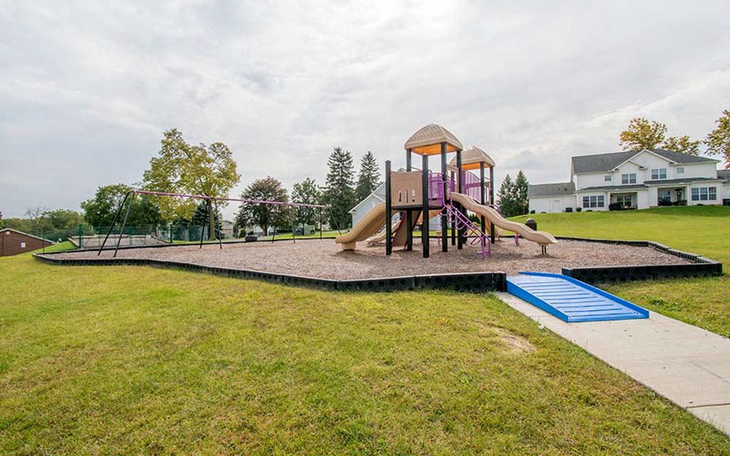 a playground with a slide and playset in a yard