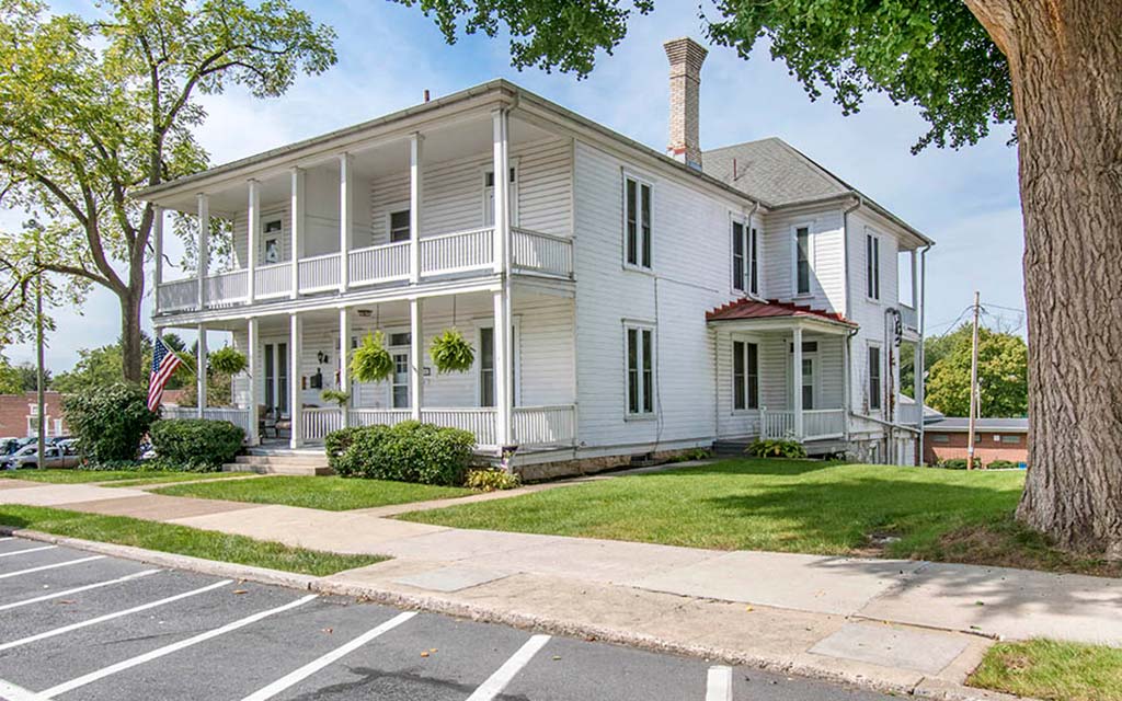 a large white house with a porch and a sidewalk