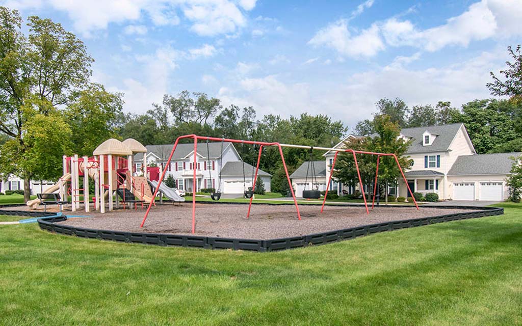 a swing set in a park with houses in the background