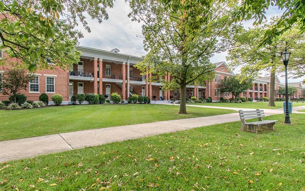 a bench sits in the grass in front of a building