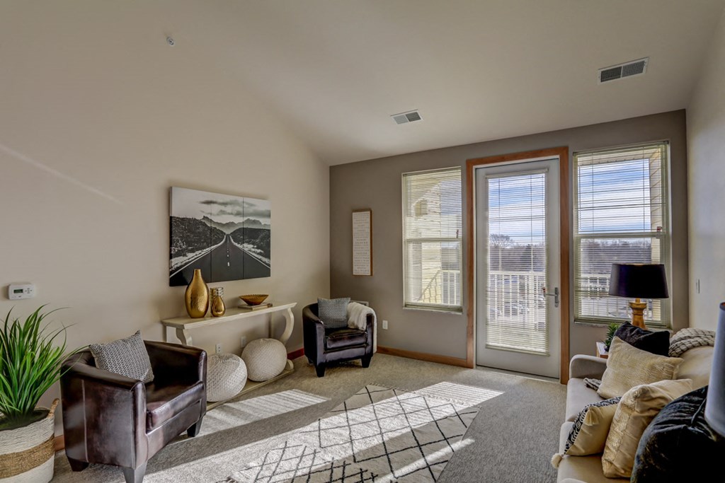 a living room with a couch and chairs and a door to a balcony