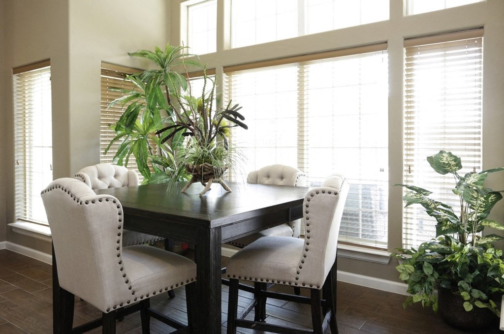 a dining room with large windows and a table with white chairs