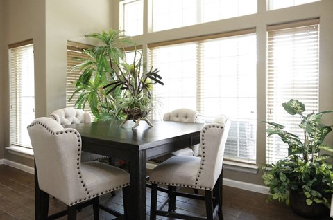 a dining room with large windows and a table with white chairs