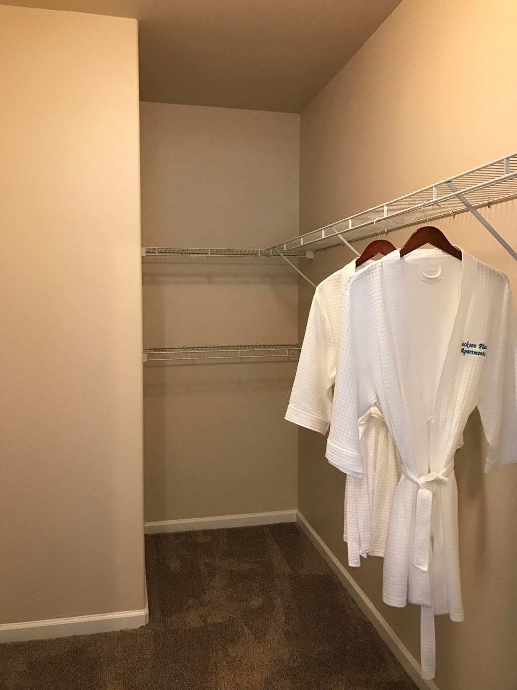 a walk in closet with white robes and hangers