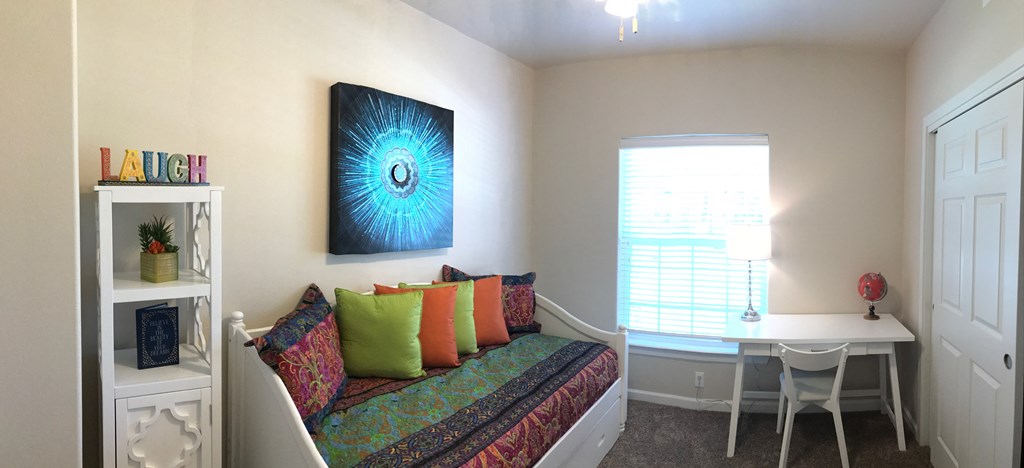 a living room with a couch and a desk and a window