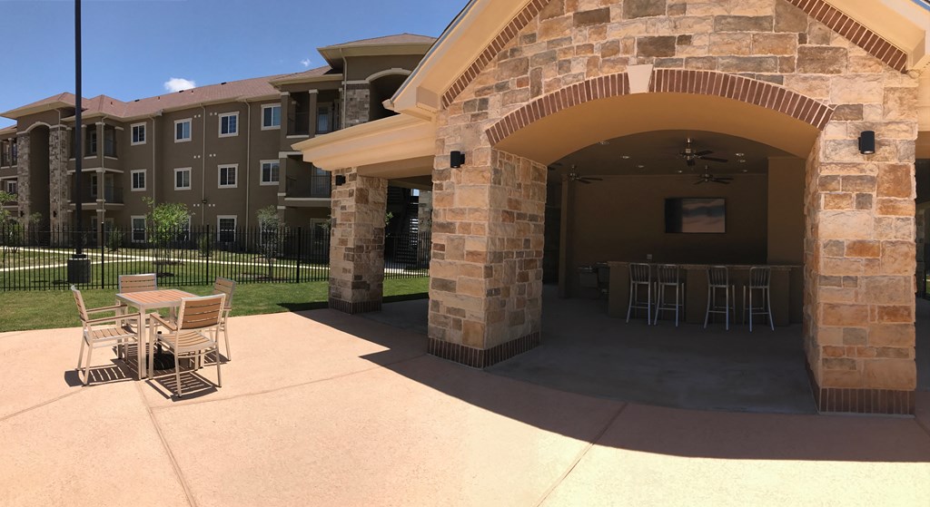 a patio with tables and chairs outside of an apartment building