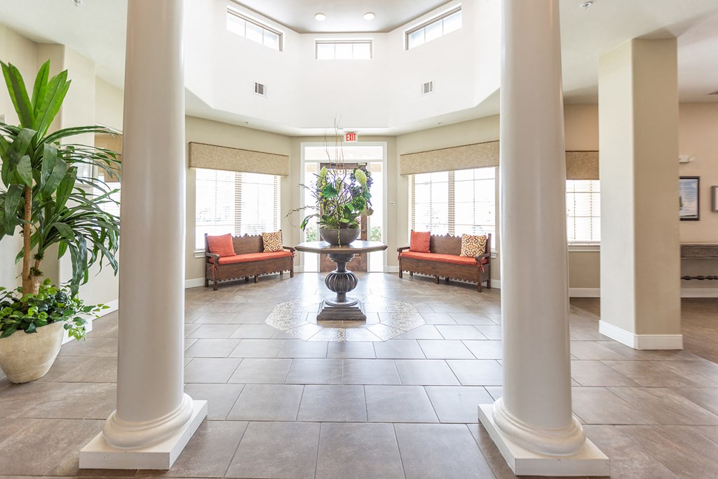 a lobby with columns and a vase with flowers in the center