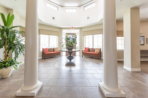 a lobby with columns and a vase with flowers in the center