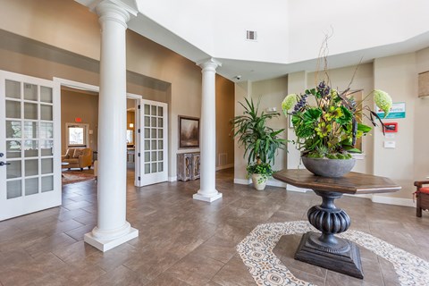 a lobby with pillars and a table with a potted plant
