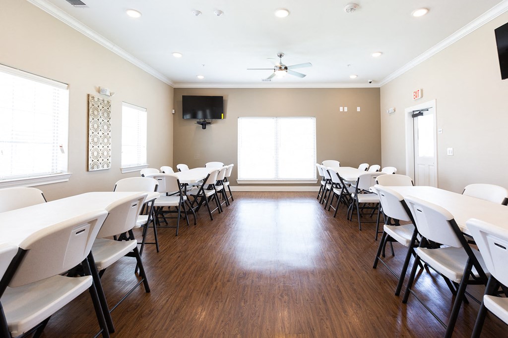 a conference room with white tables and chairs and a ceiling fan