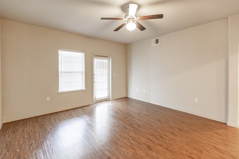 an empty living room with wood floors and a ceiling fan
