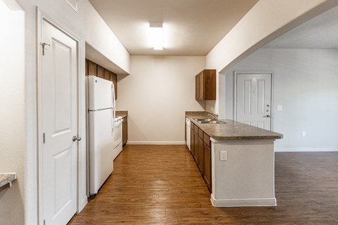 an empty kitchen with white appliances and a wood floor
