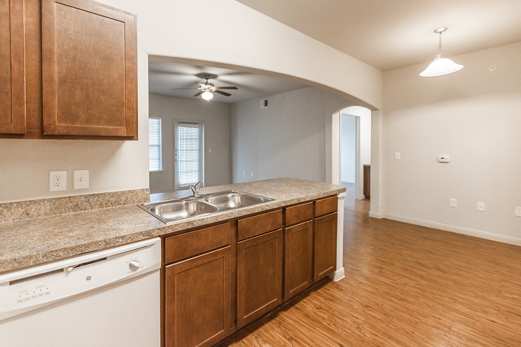an empty kitchen with wood flooring and granite counter tops