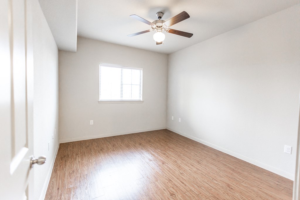 an empty room with wood floors and a ceiling fan