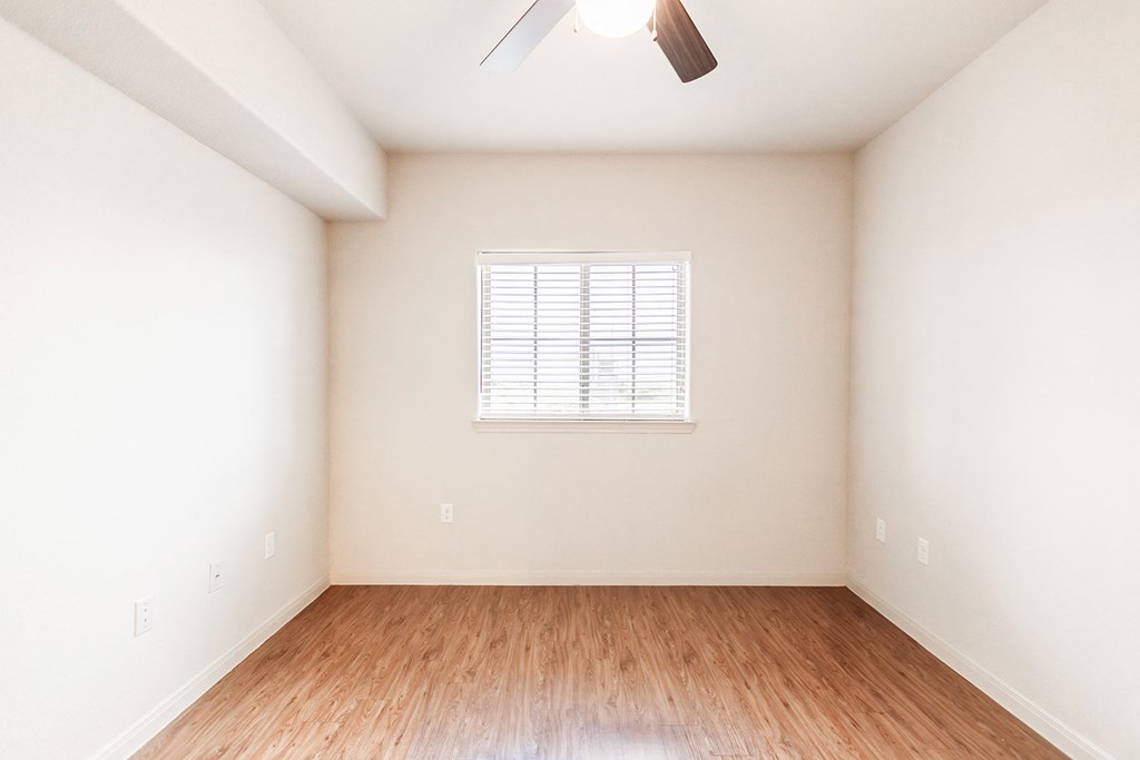 an empty room with wood floors and a window