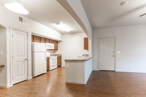 an empty kitchen with white appliances and a wood floor