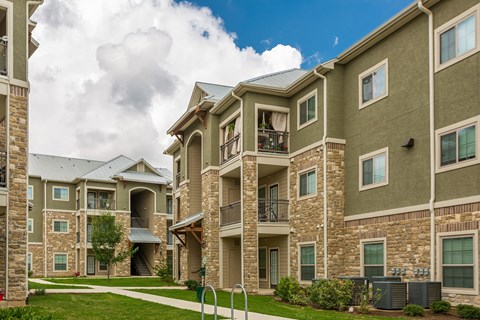 an apartment building with a walkway and grass