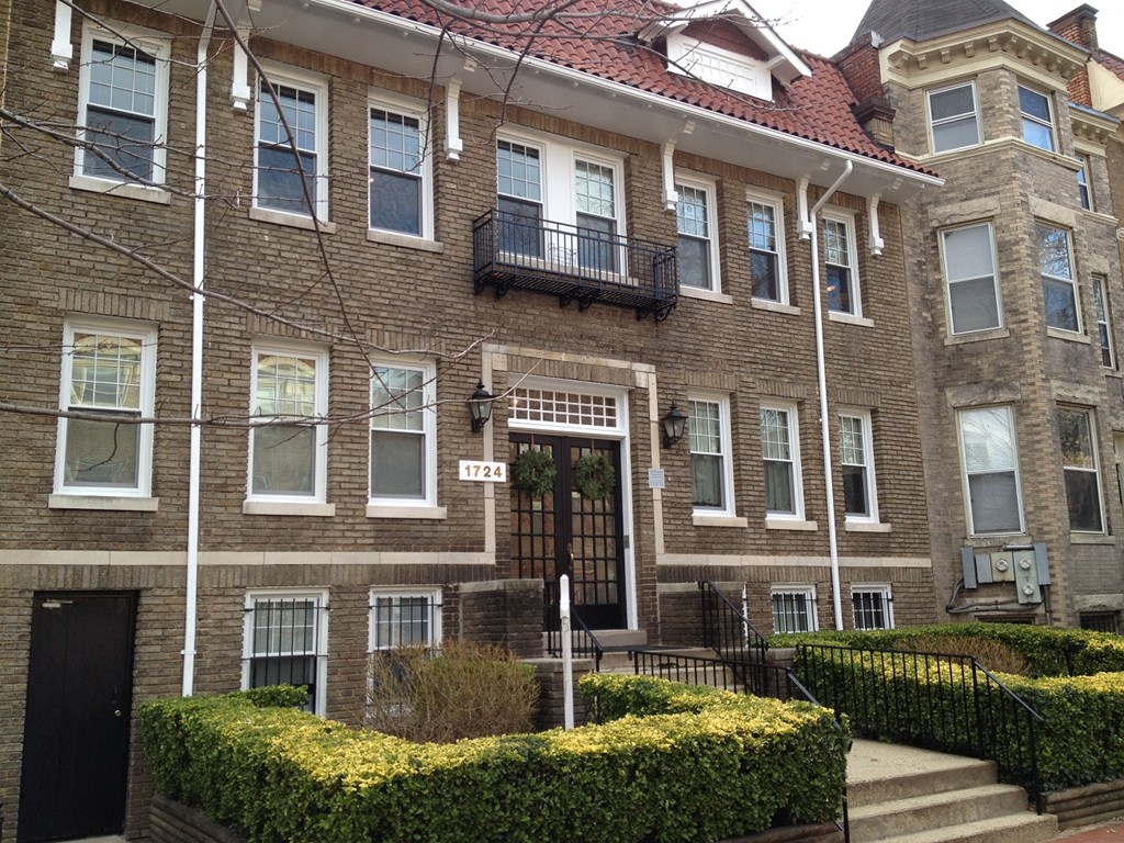 the front of a brick house with a brown door