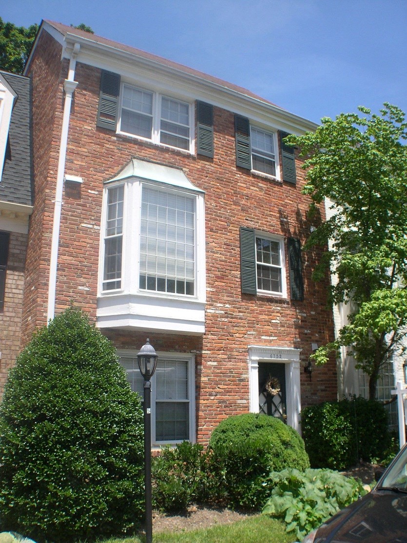 the front of a brick house with white windows