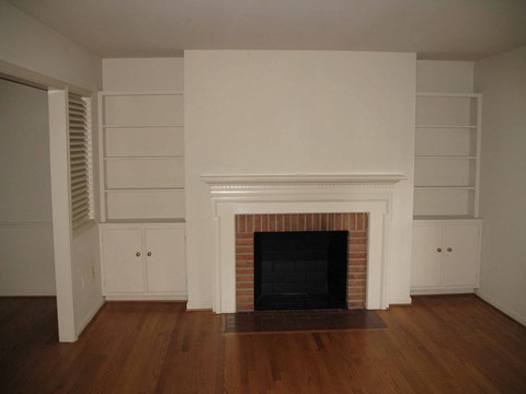 an empty living room with a fireplace and white walls