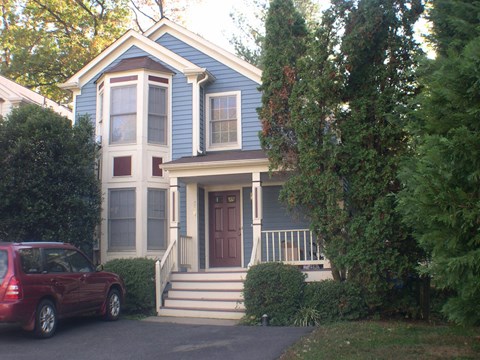 a blue house with a red car parked in front of it