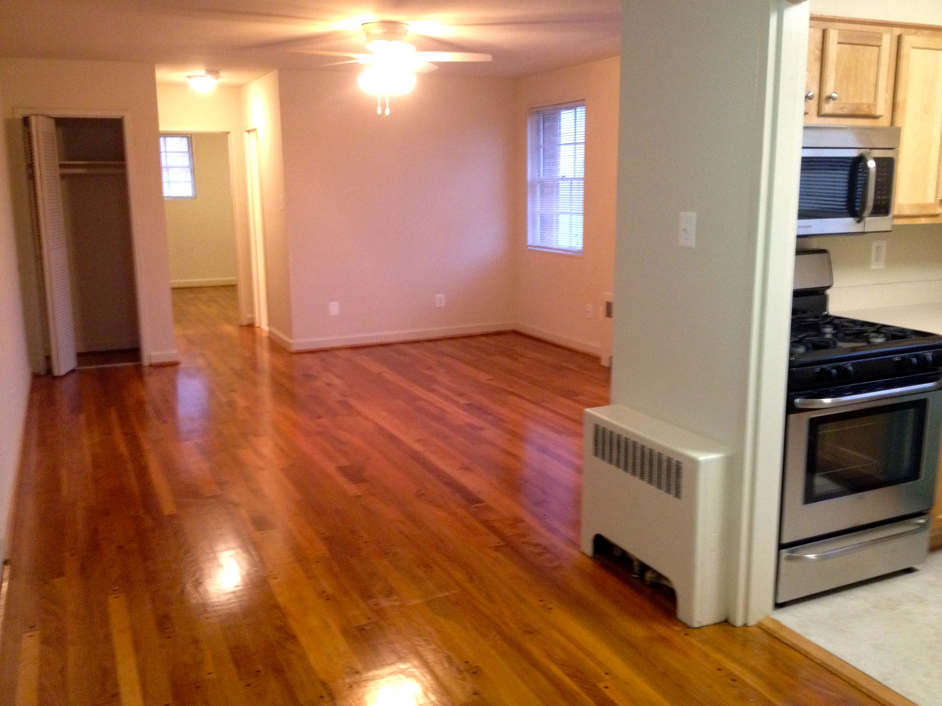 an empty living room and kitchen with wood flooring