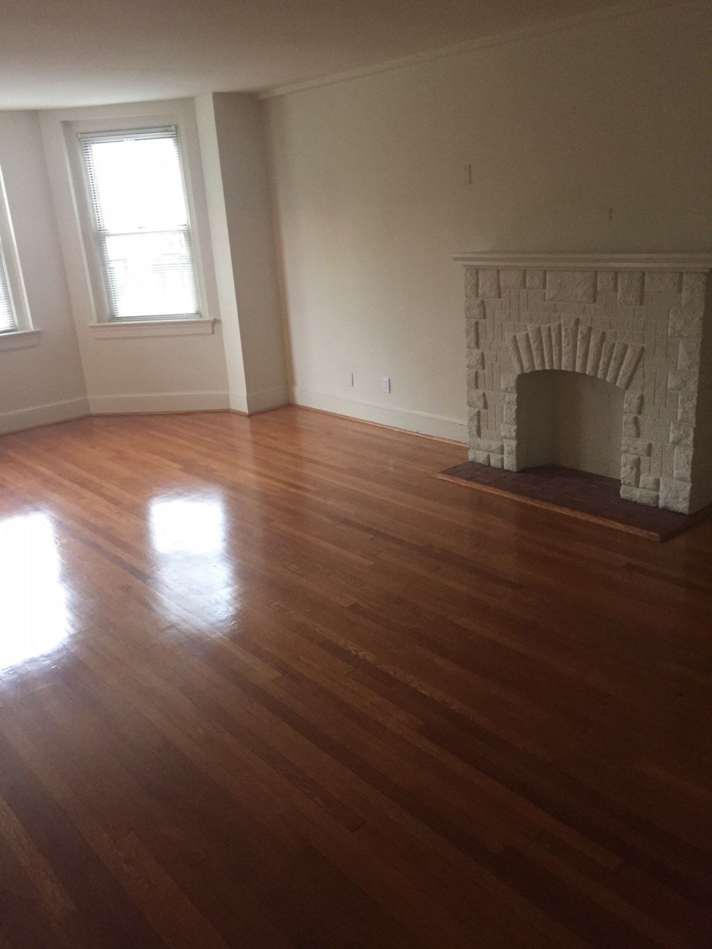 an empty living room with a fireplace and wooden floors
