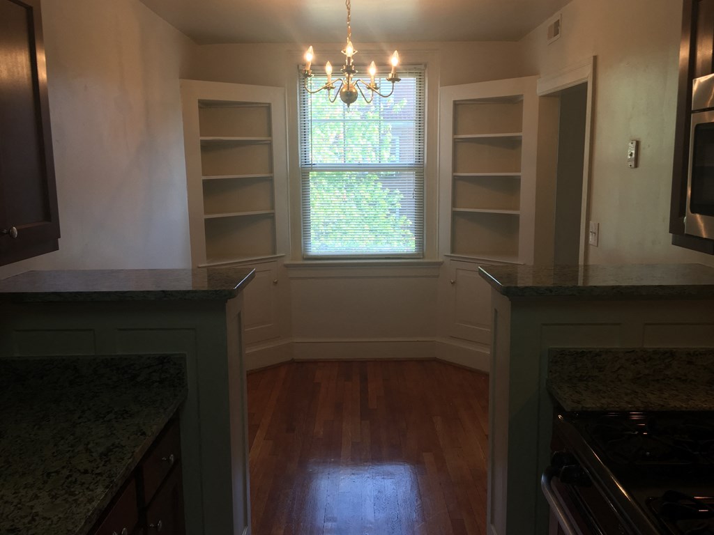 an empty kitchen with white shelves and a window