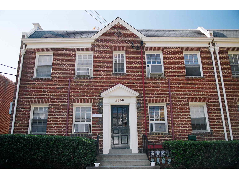 the front of a red brick house with a blue door