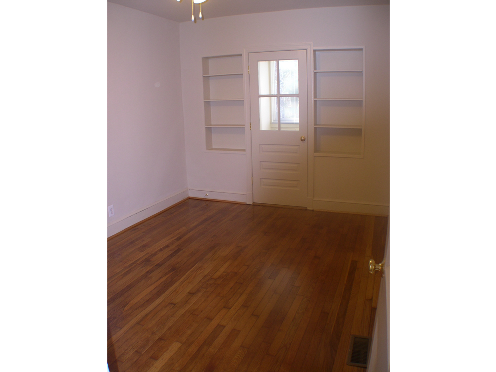 an empty living room with a wooden floor and a white door