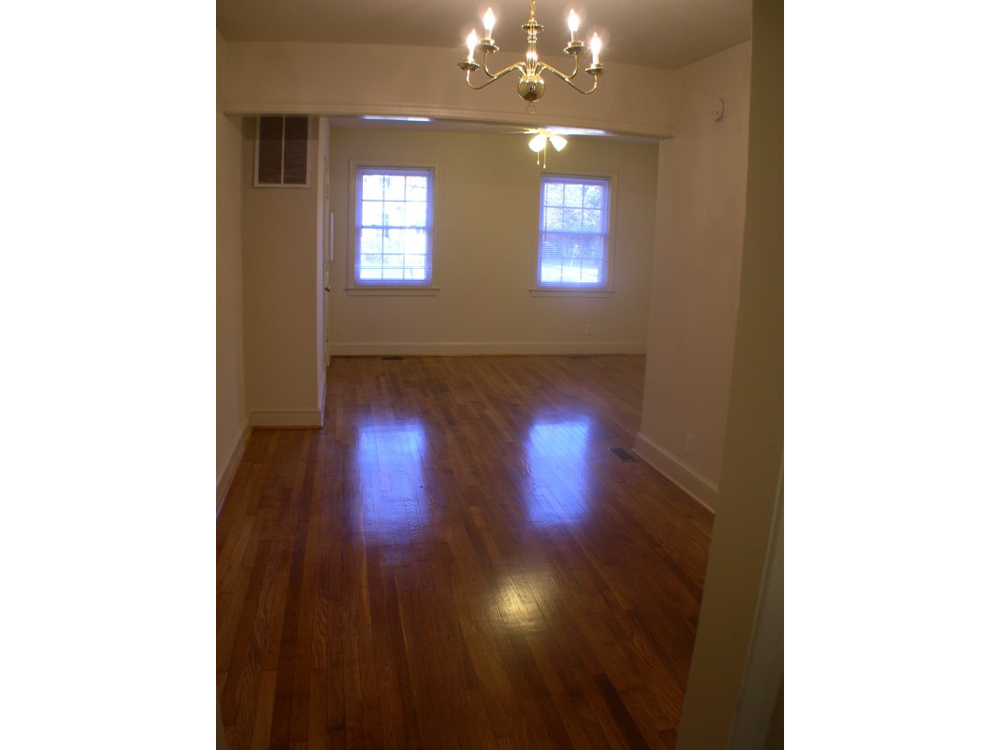 an empty living room with wood floors and a chandelier