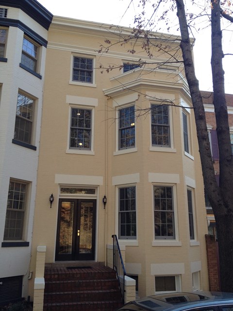 the front of a yellow house with stairs and a door