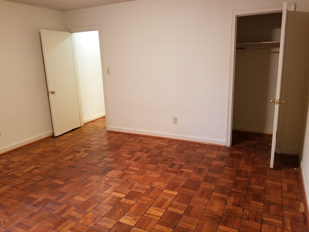 an empty living room with wood flooring and a closet