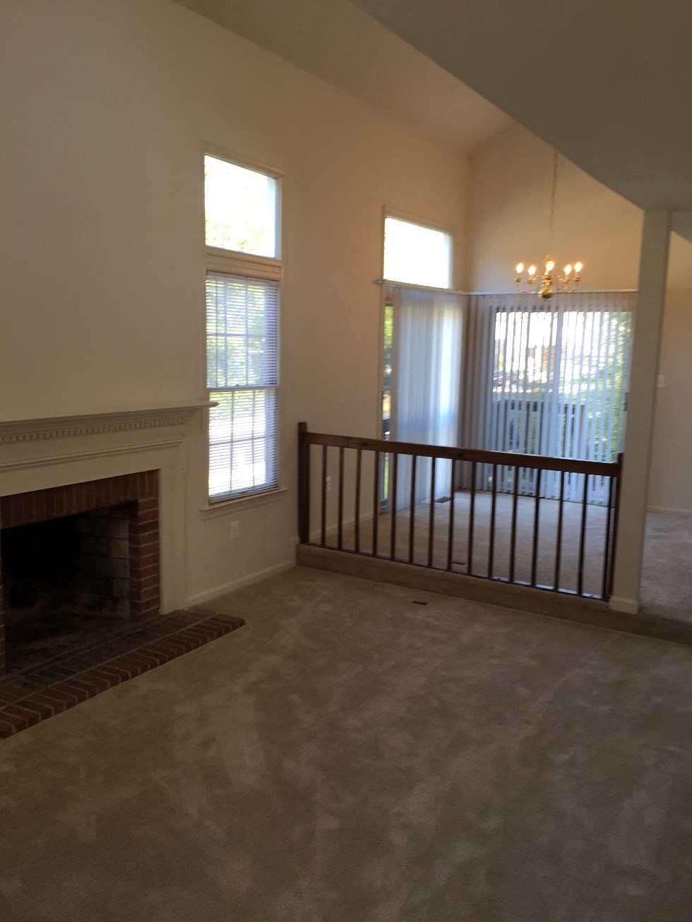 an empty living room with a fireplace and a balcony