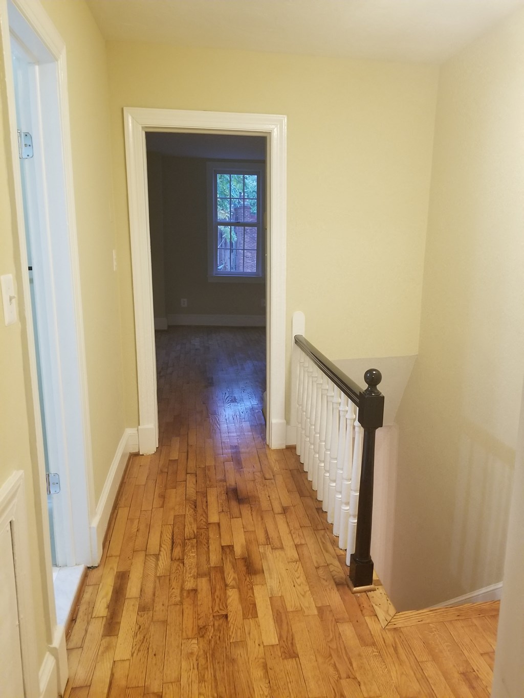a hallway with a hard wood floor and a door to a room with a window