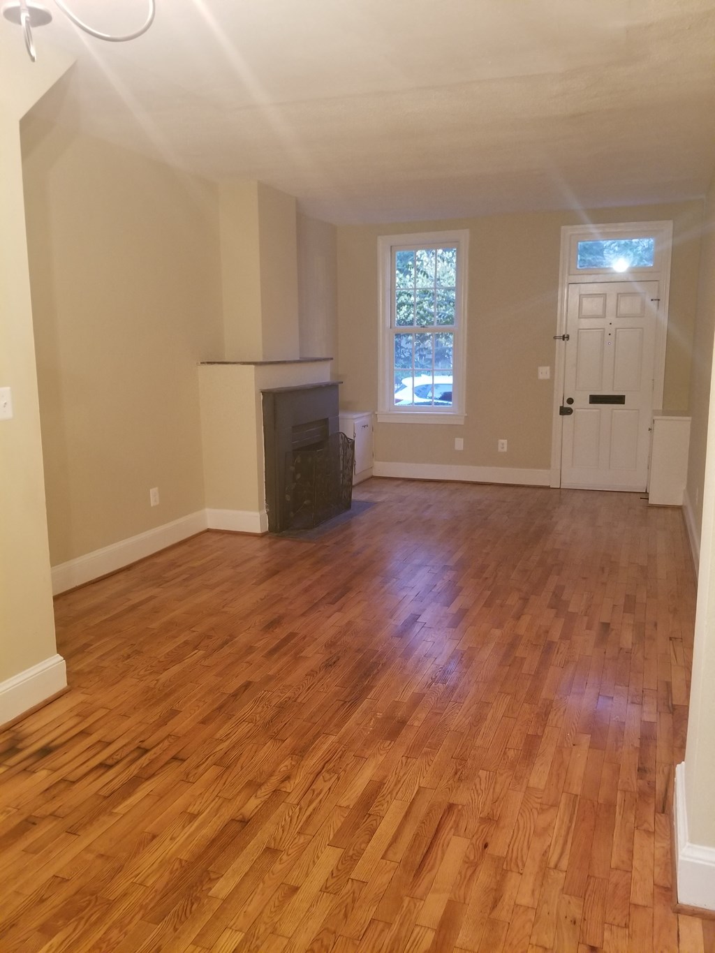 an empty living room with wooden floors and a fireplace