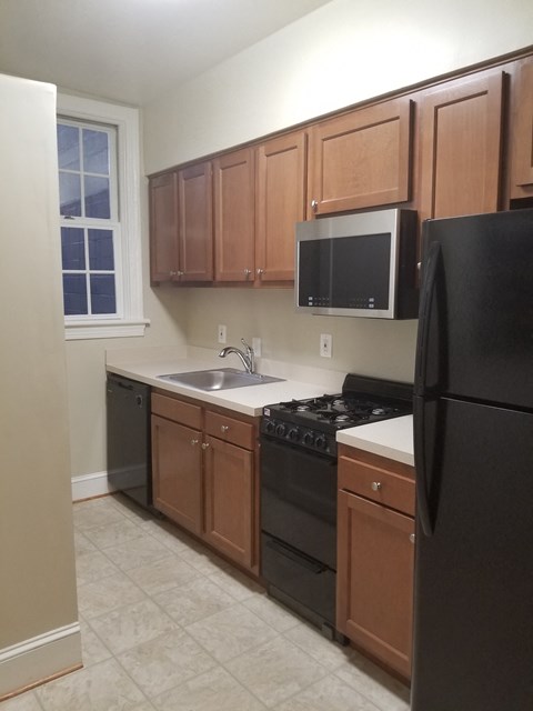an empty kitchen with black appliances and wooden cabinets