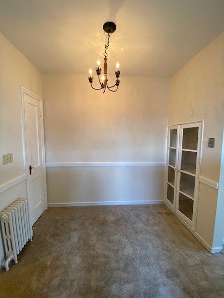 a empty living room with a chandelier and a book shelf