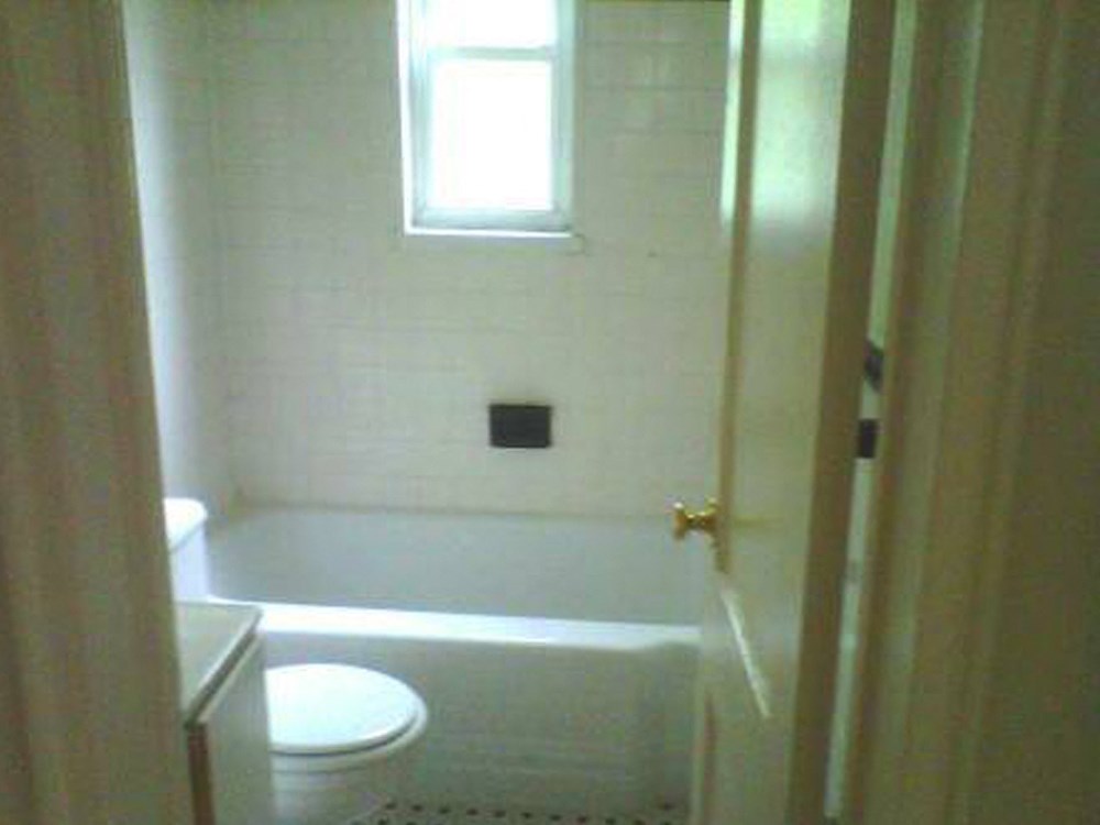 a white bathroom with a toilet and a window