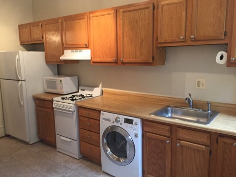 a kitchen with wooden cabinets and white appliances and a washing machine