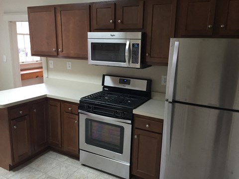 an empty kitchen with stainless steel appliances and wooden cabinets