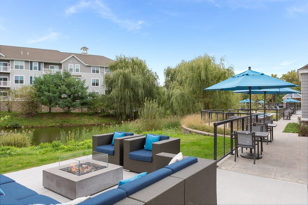 a patio with a fire pit and chairs and umbrellas