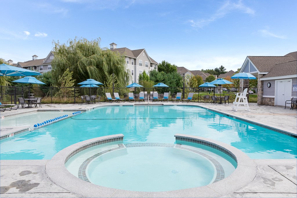 a swimming pool with chairs and umbrellas in front of a house