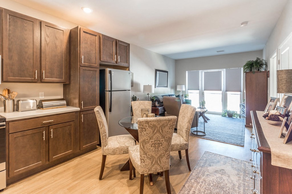 a kitchen and living room with wooden cabinets and a table and chairs