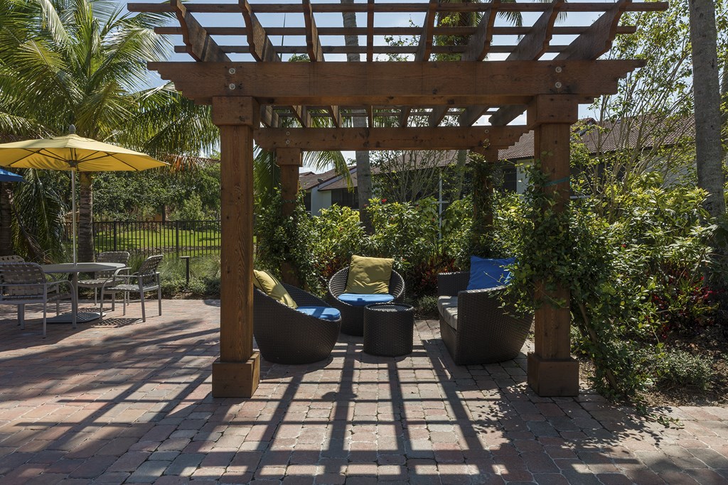a pergola over a patio with chairs and plants