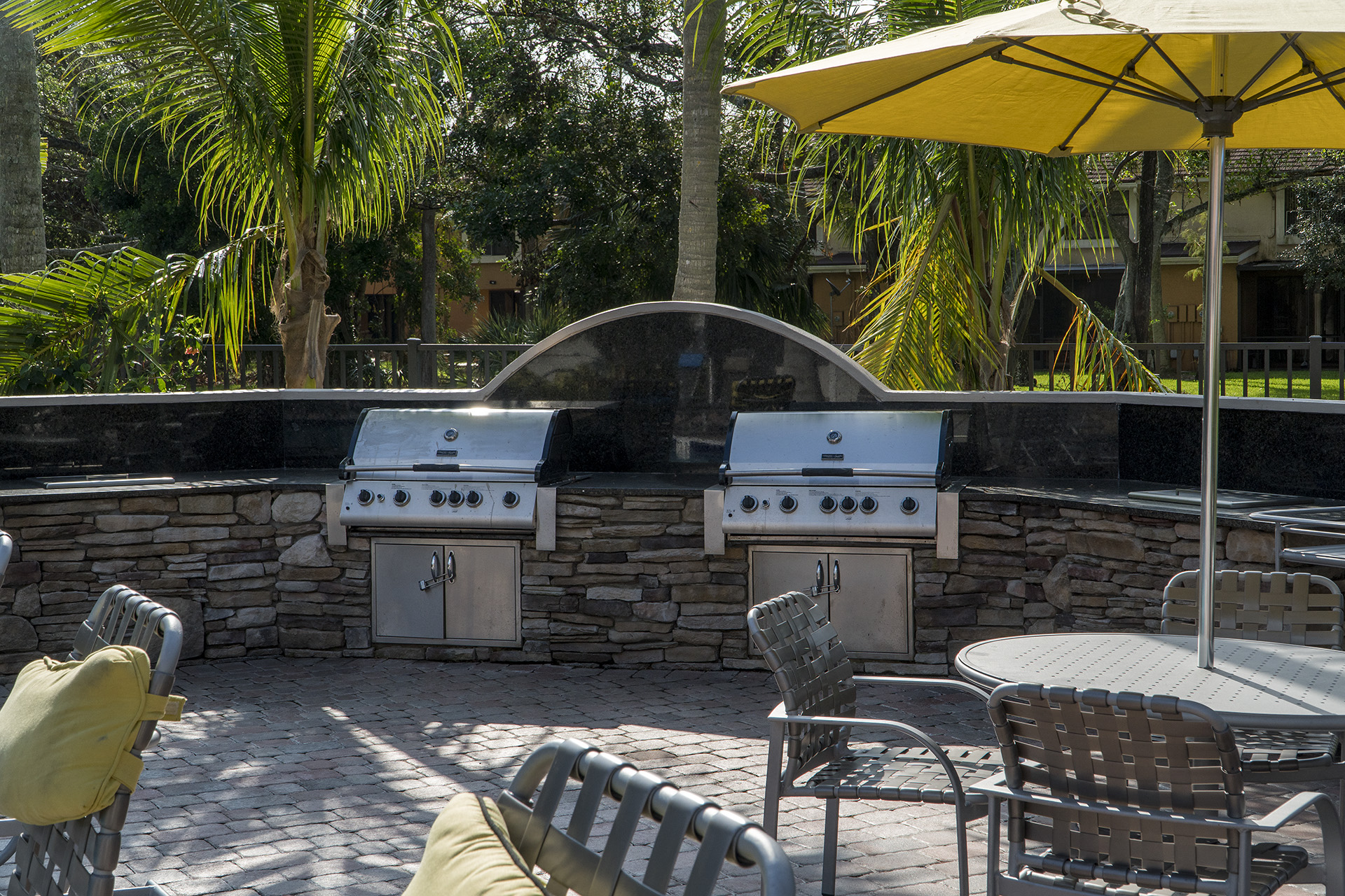 a patio with a barbecue grill and chairs and umbrellas
