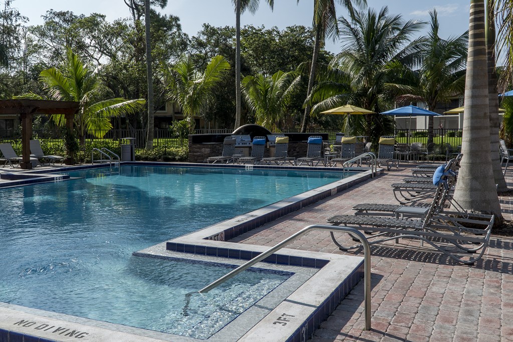 a swimming pool with chairs and trees in the background